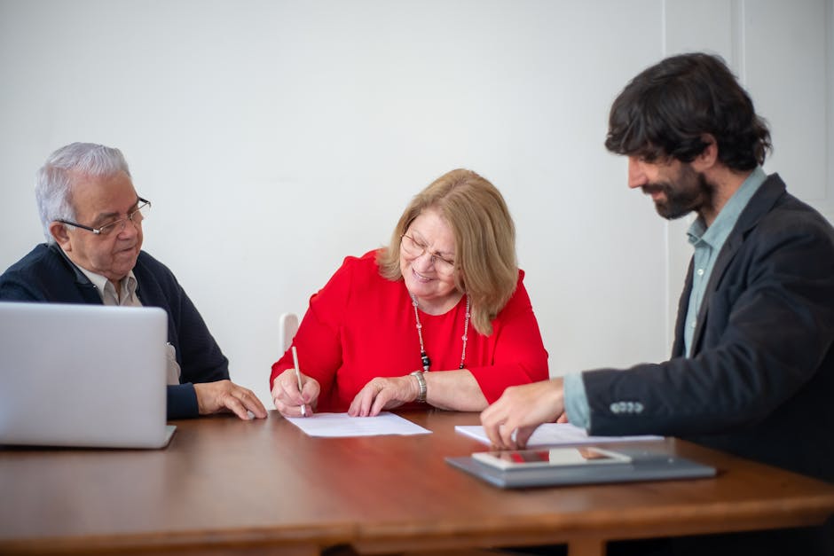 Senior business professionals signing documents during a meeting in a bright office.